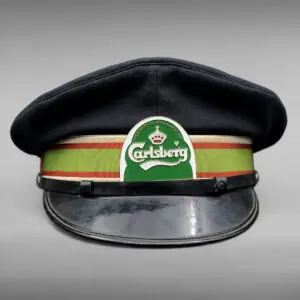 Original Carlsberg kuskekasket fra Jensen & Jørgensen, København – vintage uniformshue i str. 60 med klassisk grønt og rødt bånd og Carlsberg-logo.