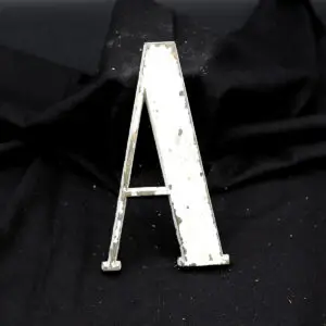 Overmalet messing-facadebogstav “A” med rå patina og originale gevindstænger.