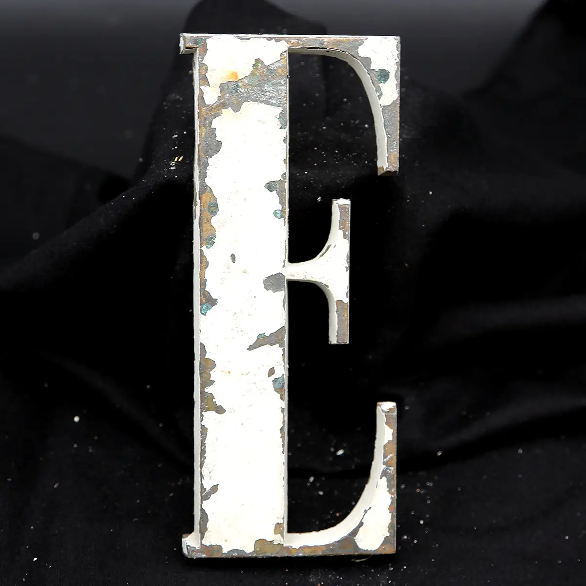 Overmalet messing-facadebogstav “E” med rå patina og originale gevindstænger.