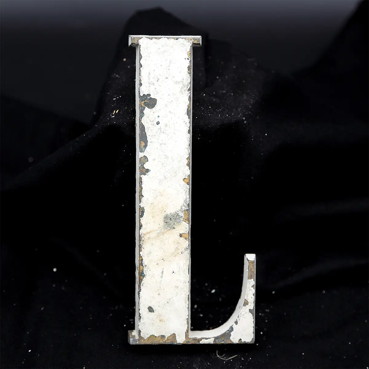 Overmalet messing-facadebogstav “L” med rå patina og originale gevindstænger.