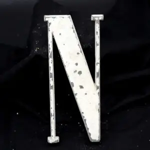 Overmalet messing-facadebogstav “N” med rå patina og originale gevindstænger.