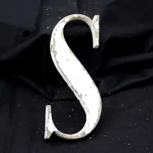 Overmalet messing-facadebogstav “S” med rå patina, afskallet maling og originale gevindstænger.