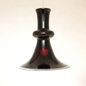 Holmegaard Etude pendel i aubergine glas med let asymmetrisk farvefordeling – mørk og elegant slukket, med varm vinrød glød når lyset tændes.