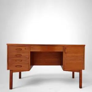 Fritstående dansk teakskrivebord fra 1960’erne med fem skuffer, skab og hylder på bagsiden.